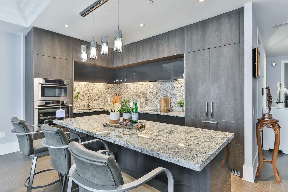 Speckled white and grey granite island and matching backsplash with grey wood cabinetry
