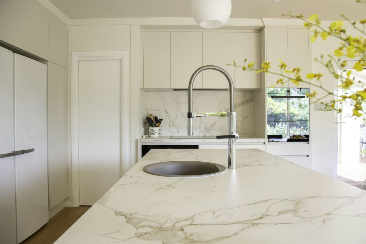 White marble-look island with gold-toned veining and an undermount round sink